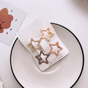 Set of four star-shaped matte hair clips in milk tea colors on white display card