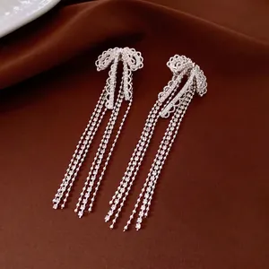 Elegant silver bow earrings with long sparkling rhinestone tassels on velvet