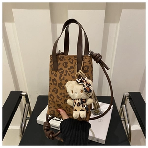 Detail of leopard print crossbody bag with cute teddy bear charm accessory