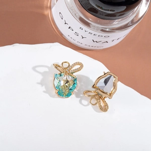 Macro detail of gold leopard bow earrings with colorful mocha crystals on a stone