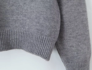 Gros plan des poignets côtelés et de l'ourlet d'un cardigan en tricot gris texturé