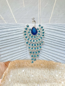 Close-up of a silver evening clutch featuring a peacock buckle with blue crystals