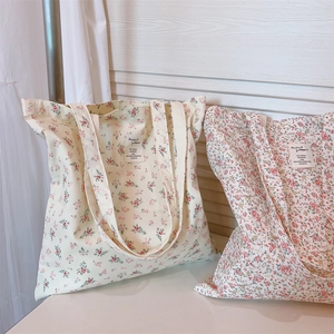 Detail of floral cotton tote bag texture and brand label on a minimalist surface