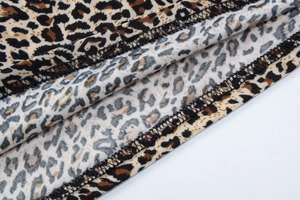 Dettaglio macro della cucitura overlock su tessuto con stampa leopardata da donna