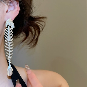 Detail of silver fishbone drop earring with rhinestones and white teardrop pearl on model