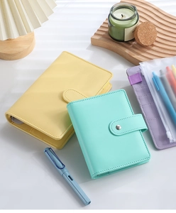 Flat lay of macaron PU leather budget planners in yellow and green on a bright desk