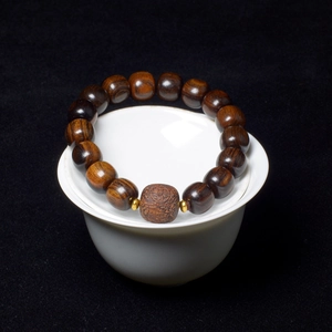 Zen style dark brown agarwood beaded bracelet with carved center bead and gold accents