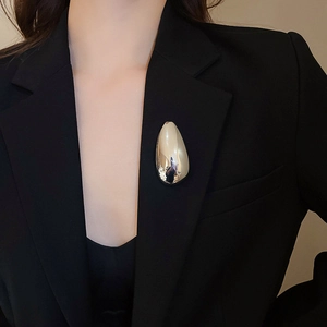 Macro detail of large silver irregular oval brooch pinned on a black suit lapel