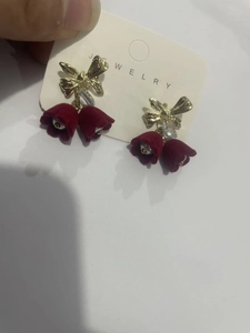 Detailed close-up of wine red velvet flower tassel earrings with golden bow design