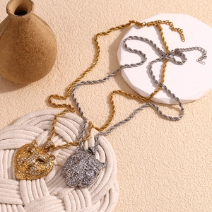 Detail of 18K gold and silver leopard head pendants with crystals on twist chains