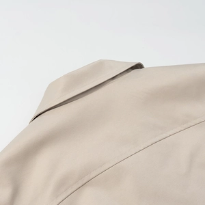 Detail view of the stitching and fabric texture on the collar and shoulder of the beige jacket