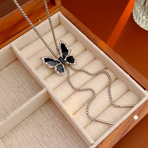 Macro shot of silver butterfly necklace with black wings on linen box padding