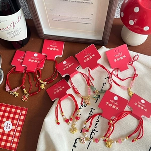 Detailed close-up of woven red string bracelets with gold zodiac charms on display cards