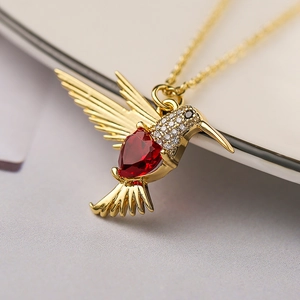 Close-up of hummingbird pendant with a red heart gem and sparkling cubic zirconia details