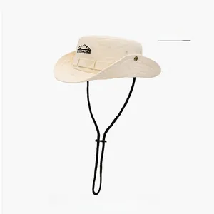 Détail du chapeau de soleil beige avec broderie de montagne et cordon coupe-vent réglable
