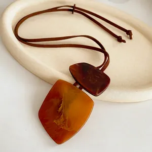 Irregular resin square pendant necklace with amber texture on brown suede cord