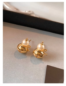 Détail macro de boucles d'oreilles gourde dorées avec perles et petits diamants