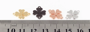 Macro shot of clover-shaped metal connector charms in gold, black, rose gold, and silver