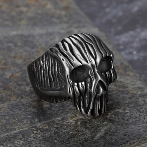 Vintage punk skull ring for men in antique silver finish on a dark stone background
