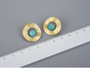 Detailed size measurement of gold geometric silver earrings with green stone on grey background