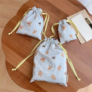 Three-piece set of blue striped cotton drawstring bags with bear print on a wooden desk