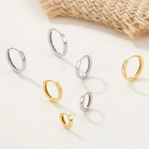 Macro shot showing S925 sterling silver stamp on minimalist gold and silver hoop earrings