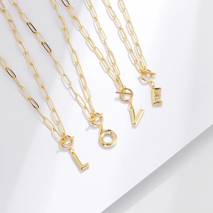 Detail of four gold paperclip necklaces with LOVE letter pendants and T-Bar clasps