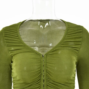 Détail d'un haut vert à col en V avec fermeture éclair et texture plissée élégante