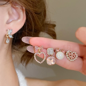 Detail of Korean style heart and bow pearl earrings set on model ear and hand