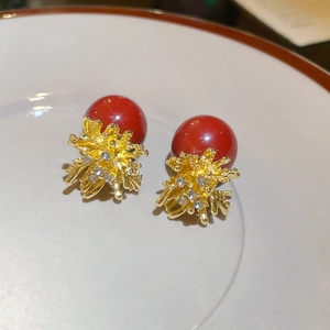 Macro detail of red pearl stud earrings with golden flower base and white crystals
