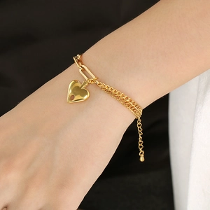 Dettaglio di un bracciale a doppio strato placcato oro 18k con ciondolo a cuore su modella