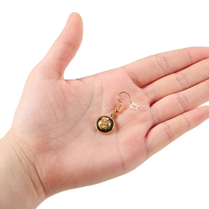 Detail of round black resin earring with gold foil accents and clear silicone back