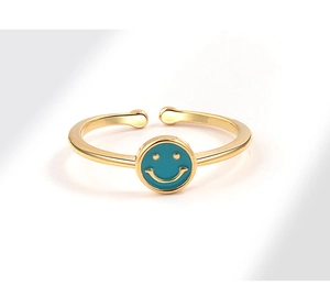 Macro shot of gold adjustable ring featuring a light blue enamel smiley face disc