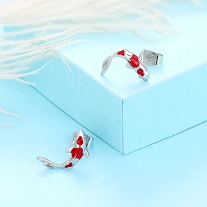 Detailed view of silver koi fish earrings with red enamel and zircon on a jewelry box