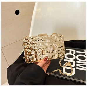 Detail of gold metallic clutch with hammered texture and elegant chain strap for evening events