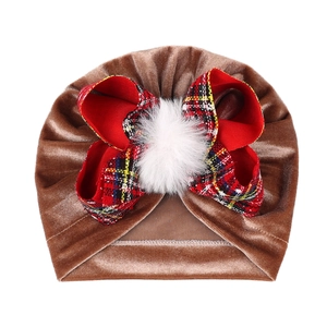 Detail of baby velvet turban hat with brown fabric and red plaid bow with pompom