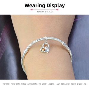 Detailed view of a silver snake chain bracelet featuring an inlaid heart pendant on a wrist