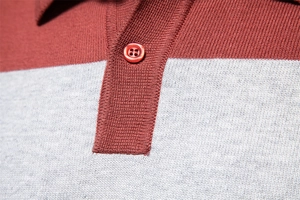 Makroaufnahme von Stricktextur und Knopfdetails am burgundergrau gestreiften Polohemd