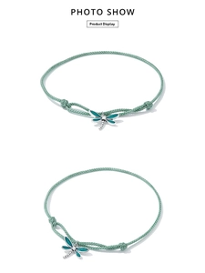 Detail of green woven cord bracelet featuring a dragonfly charm with teal enamel and zircon