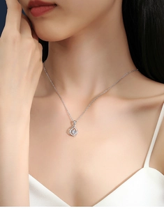 Detailed close-up of a silver water drop pendant with a shimmering zircon on a female model