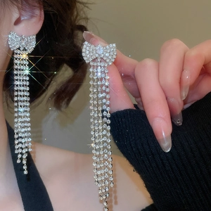 Detail shot of silver bow earrings featuring long sparkling tassel chains and crystals