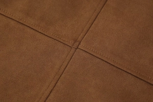 Macro view of brown faux suede fabric with detailed cross-stitch reinforced seams
