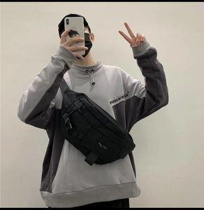 Dettaglio di un marsupio tattico in tela nera con tasche a zip e cinghie con fibbie