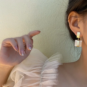 Boucles d'oreilles carrées minimalistes en métal doré et texture coquille rose sur modèle