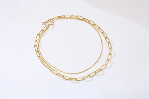 Detail of gold double-layered necklace featuring a paperclip chain and delicate fine chain