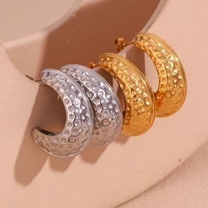 Détail de boucles d'oreilles en C avec texture martelée en finitions or et argent