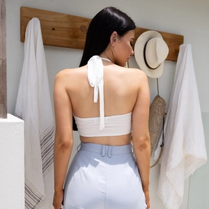 White backless halter crop top with tie detail and light blue high waist trousers