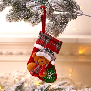 Christmas stocking with brown bear and tree on snowy pine branch near fireplace
