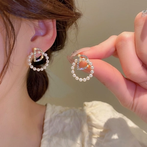 Détail de boucles d'oreilles perles rondes avec un logo D serti de cristaux