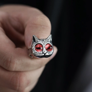 Detail of vintage silver owl ring featuring striking red eyes and intricate metal etching